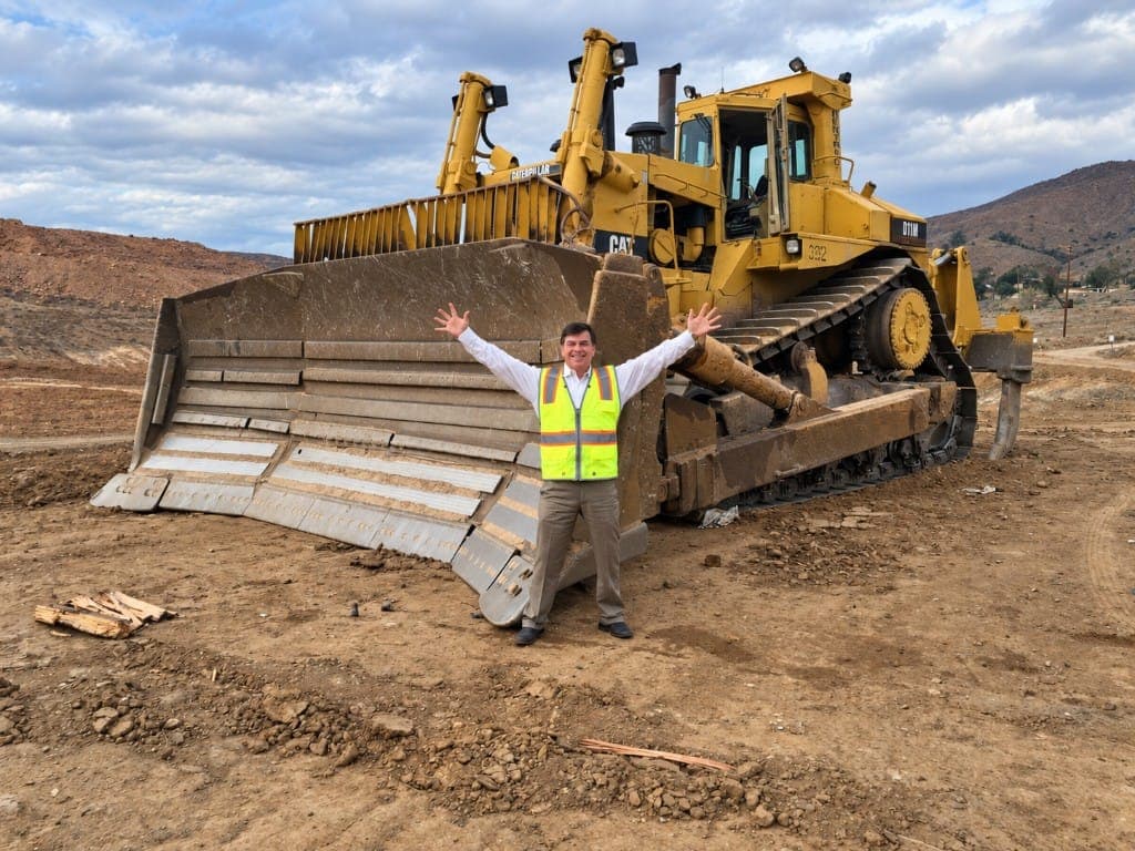 Brian Woods standing in front of a Caterpillar bulldozer on a development site