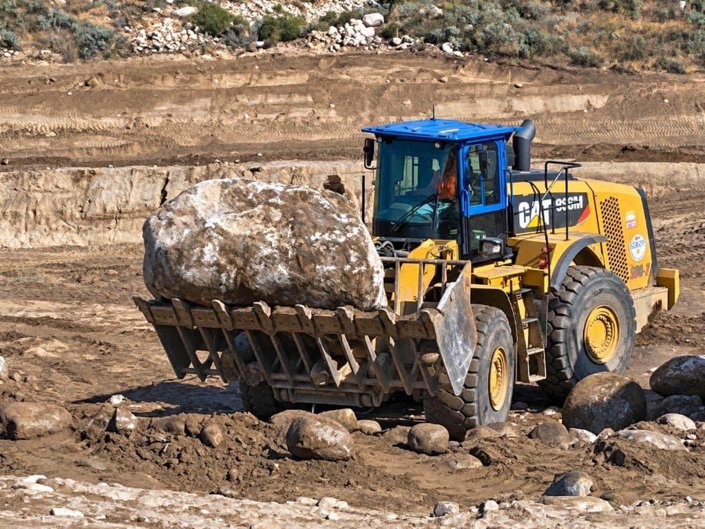 Wheel loader carrying a large boulder during site earthwork